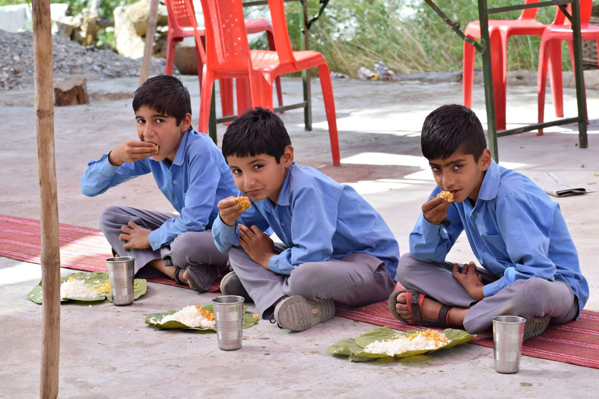 Schoolboys in uniform eating a meal outdoors