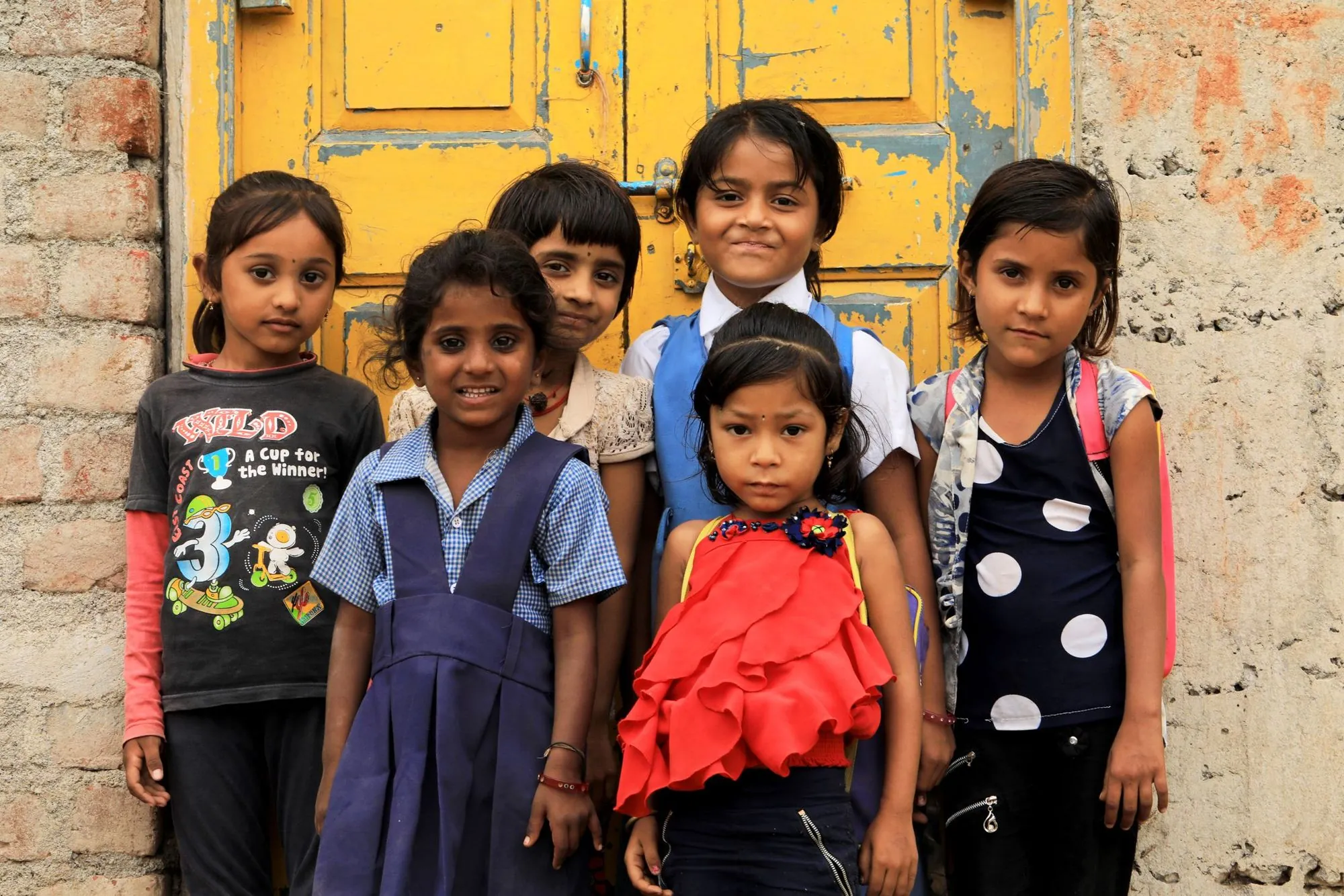 Children smiling at a yellow door